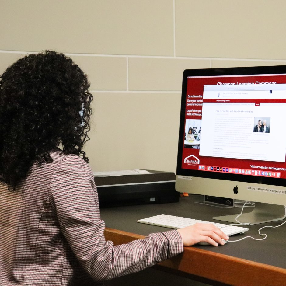 Person sitting in front of a desktop computer with the Chapman Learning Commons website open.